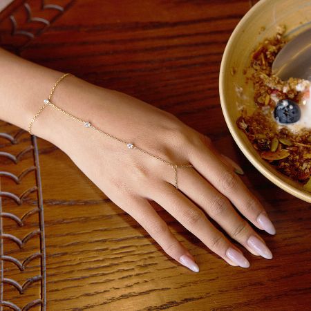 Gold Plated Stainless Steel Cubic Zirconia Hand Chain Bracelet for Women, Set of 5 - A close-up product shot of a gold-plated stainless steel hand chain bracelet with a connected finger ring, featuring delicate cubic zirconia stones.