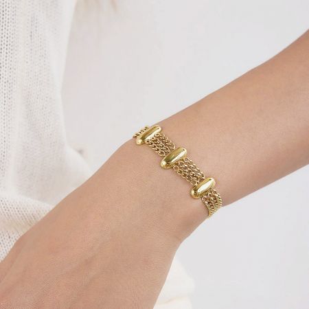 Close-up of the layered gold stainless steel bracelet set worn on a wrist.