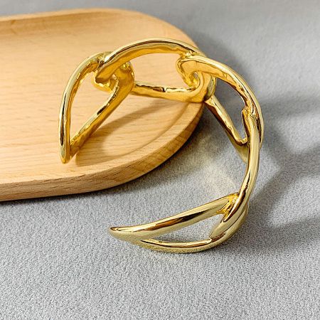 A unique gold-colored bracelet with a distinctive curved design.