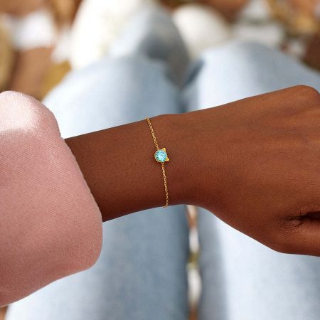 Close-up of the gold-tone cat bracelet with a blue CZ stone worn on a wrist, showcasing its elegant fit.
