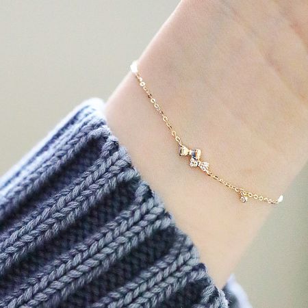Model wearing the gold-colored sterling silver bow charm bracelet.