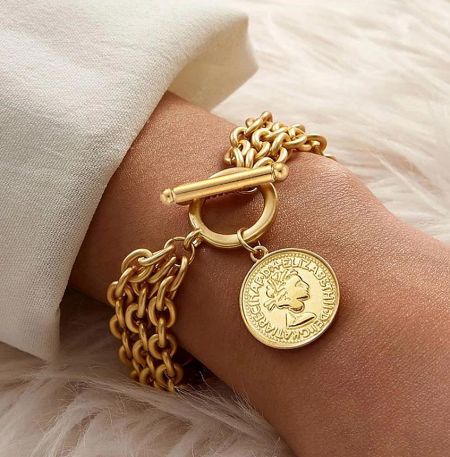 Close-up of the gold coin pendant on the trendy bracelet, featuring an Elizabeth II design.