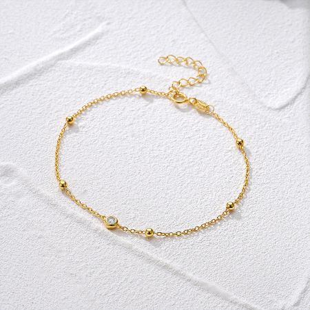 Detailed view of the gold bracelet with small beads and a sparkling zircon.