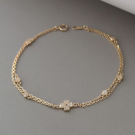 Detailed view of the double-chain construction and clasp of the gold-plated sterling silver clover bracelet.