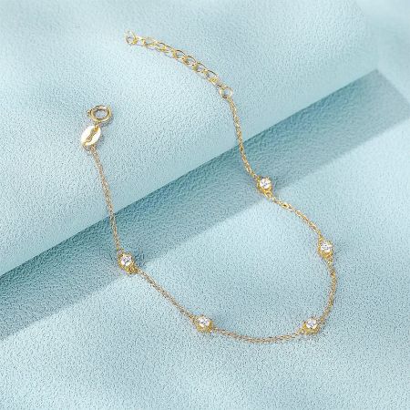 Bulk 925 Sterling Silver 5-Zircon Chain Bracelet (Set of 5) - A delicate 925 sterling silver chain bracelet in a gold finish, featuring five sparkling zircon stones, displayed on a light blue background.