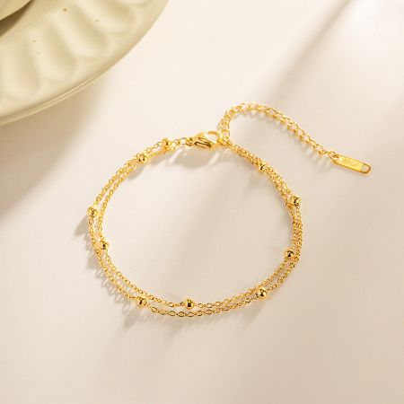 Detailed view of the gold-plated double-strand chain bracelet with small, elegant beads.