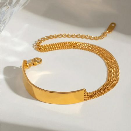 Close-up of a gold stainless steel bracelet with a flat plate and multi-strand chain design.