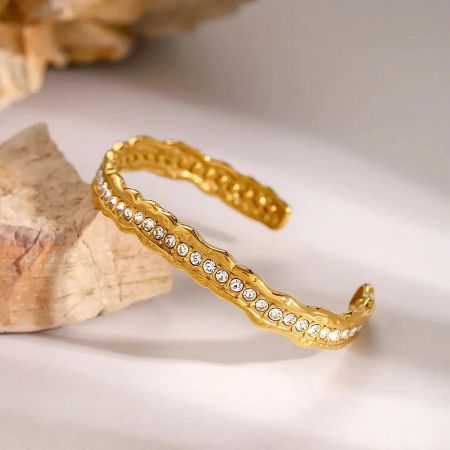 A stylish stack of gold-plated zircon cuff bracelets arranged for a luxury jewelry product shot.