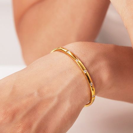 A stylish look featuring the stacked gold bangles on a wrist.