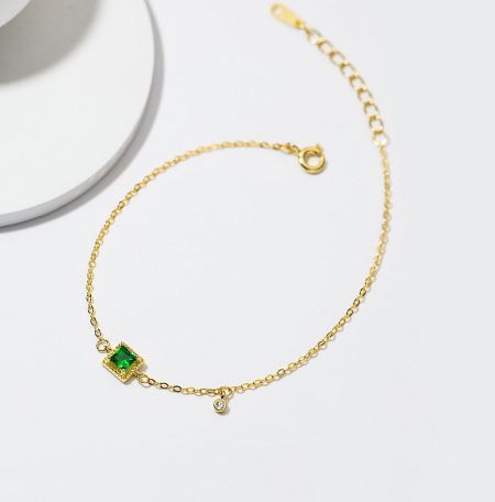 925 Sterling Silver Emerald Gold Plated Bracelet - A close-up of the 925 Sterling Silver Emerald Gold Plated Bracelet, showcasing the green emerald and clear cubic zirconia gemstones on a gold chain.