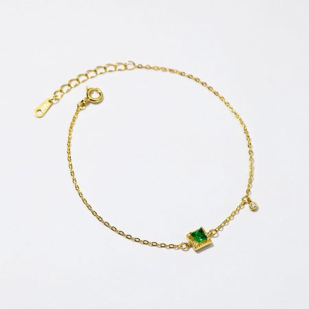 Side profile of the elegant gold bracelet highlighting the green emerald zircon.
