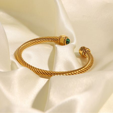 Side profile of the twisted open cuff bangle, showcasing the cylindrical setting of the green gemstone.
