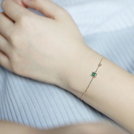 Elegant gold-plated bracelet with a square green zircon, shown on a neutral background.