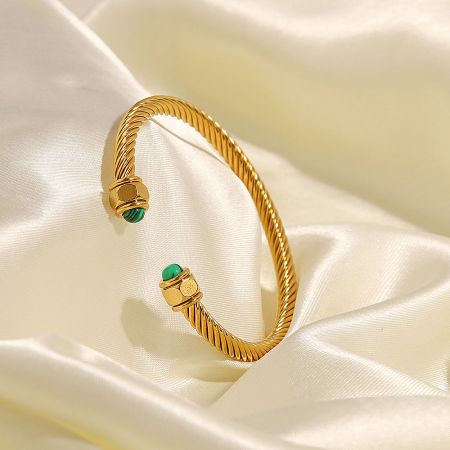 Top-down view of the stainless steel cuff bangle featuring vibrant green gemstones.