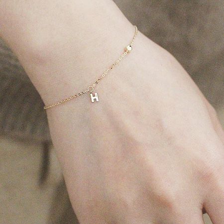Clean product shot of the gold-finished H charm bracelet against a white background.