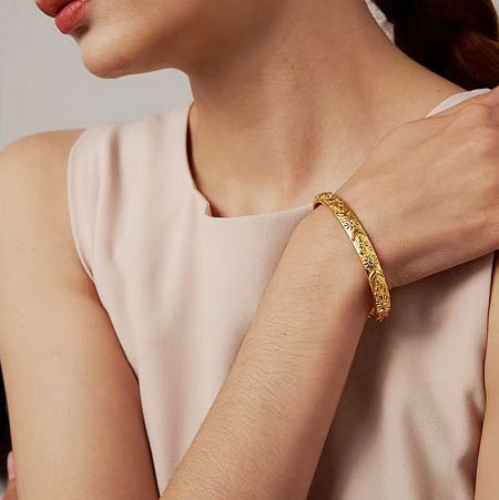 Detailed view of the intricate design on the gold sun and moon bangle.