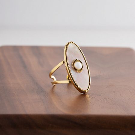 Elegant gold ring with an oval white shell stone and a delicate pearl accent.