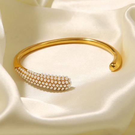 Detailed view of the elegant gold cuff bangle adorned with lustrous white pearls.