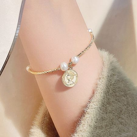 Elegant 14K gold-plated bracelet featuring freshwater pearls and a queen's head coin charm.
