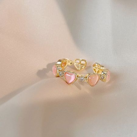 Detailed view of the gold bracelet with delicate pink heart stones.