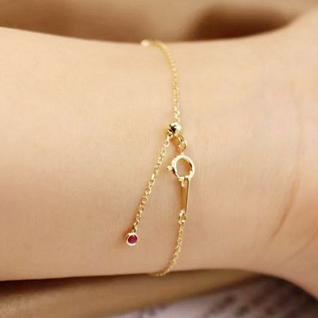 Another angle of the gold bracelet, focusing on the charm-like gemstone settings.