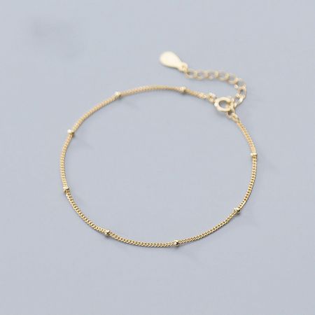 Detailed view of the gold bracelet's clasp and extension chain.