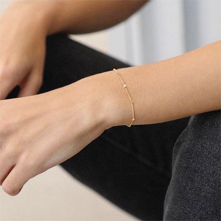 A model wearing the delicate gold bracelet with a small charm to showcase its look.