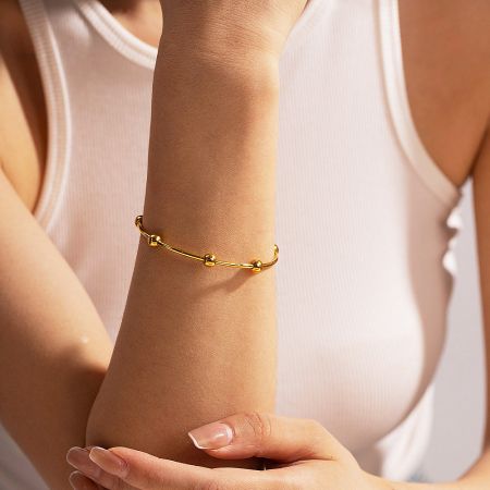 A model wearing the gold round bead open cuff bangle.
