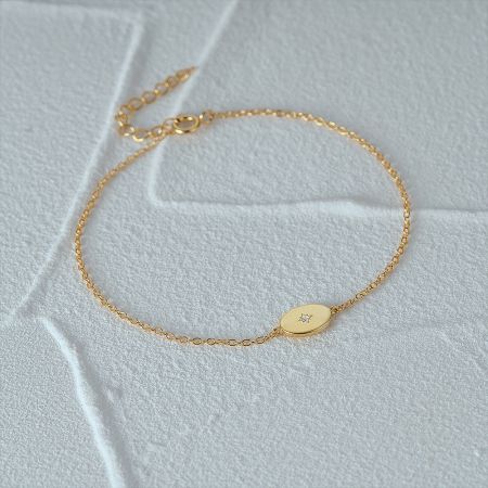 Close-up of the gold star charm bracelet with a central zircon stone on a wrist.