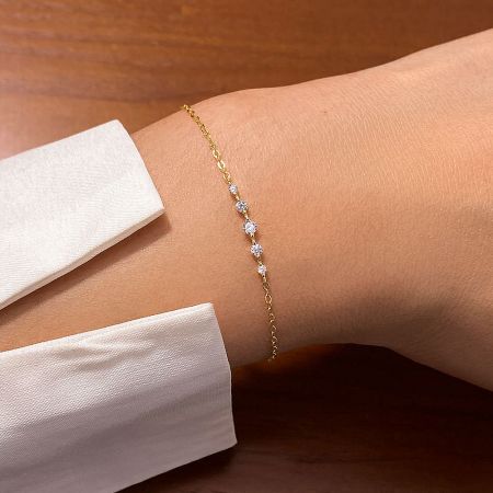 925 Sterling Silver Dainty Cubic Zirconia Chain Bracelet Set of 5 - A close-up of the 925 Sterling Silver Dainty Cubic Zirconia Chain Bracelet in gold, worn on a wrist to showcase its delicate design.