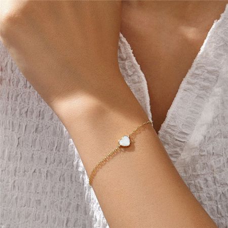 Close-up of the sterling silver bracelet with a classic white enamel heart charm on a wrist.