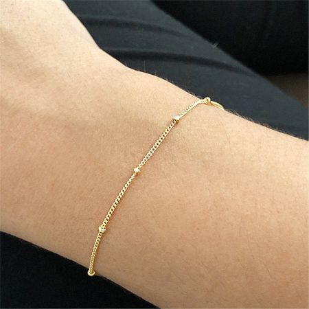 Close-up of the delicate 925 sterling silver bead bracelet in gold, worn on a wrist.