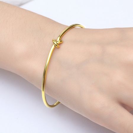 Model wearing the gold knot bangle to showcase its fit and style.