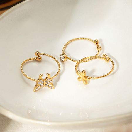 Showcase of the adjustable gold-plated rings with delicate charm designs.