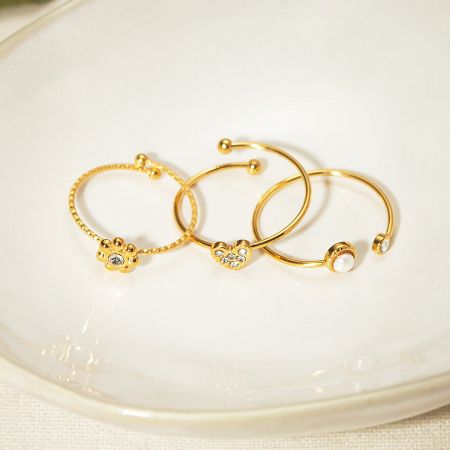 Close-up of the charming flower, butterfly, and heart motifs on the gold-plated rings.