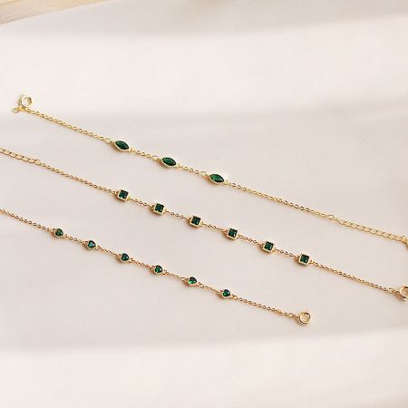 Detailed view of the three bracelet designs with unique green gemstone settings on a clean white background.