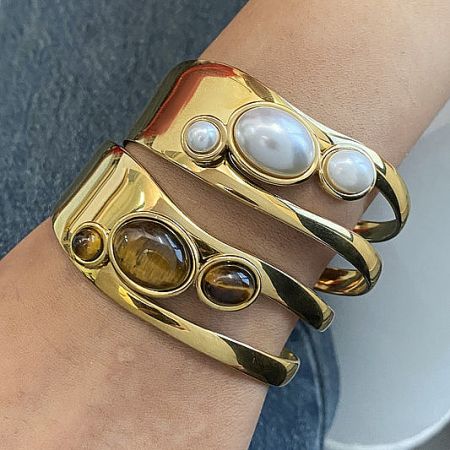 Elegant gold cuff bracelets featuring pearl and tiger's eye gemstones, available for wholesale.