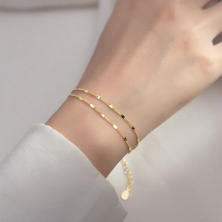 Close-up of the gold two-layer chain bracelet being worn.