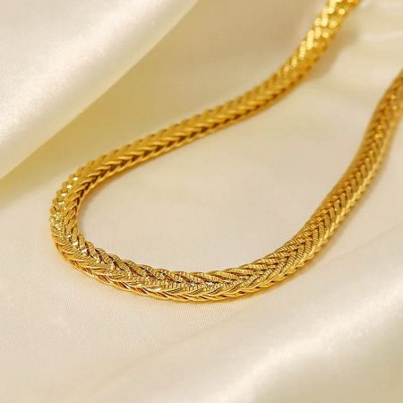 The gold rope chain necklace elegantly displayed on a satin fabric.