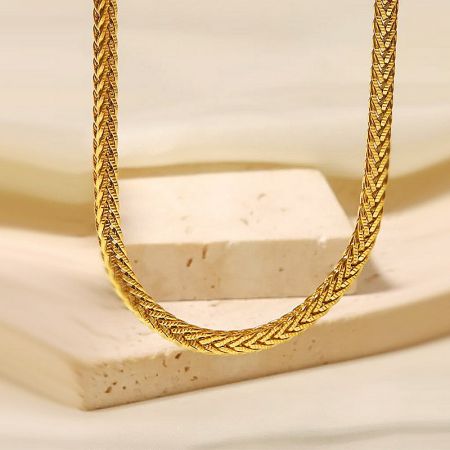 Product shot of the gold twisted rope necklace on a textured stone block.