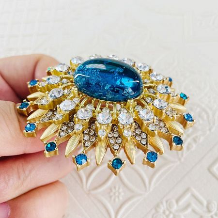 Angled view of the vintage-style gold sun brooch pin, highlighting its radiant design and sparkling gemstones.