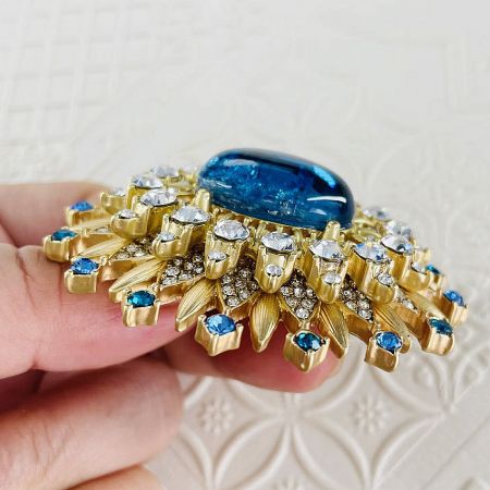 Detailed shot of the gold-plated crystal sun brooch, focusing on the craftsmanship and gemstone setting.