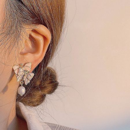 Model wearing the gold butterfly earring with a freshwater pearl, showcasing its elegant drop.