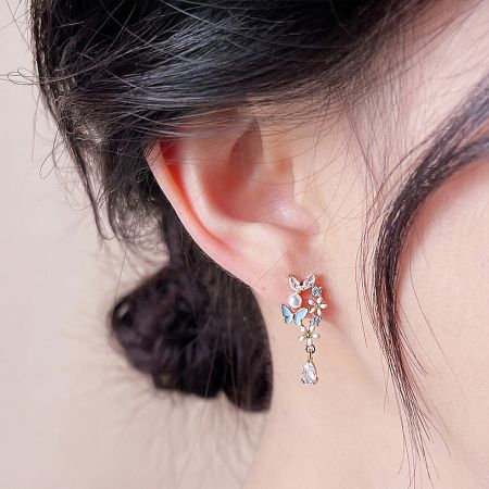 Close-up view of the gold butterfly earring showcasing the intricate details of the pearls and gemstones.