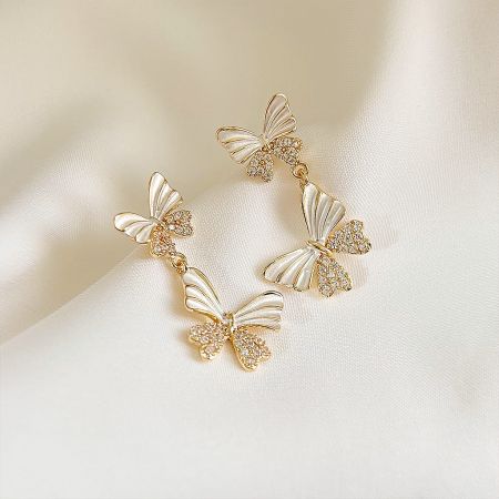 Close-up of the gold butterfly earrings highlighting the white wings and clear gemstones.