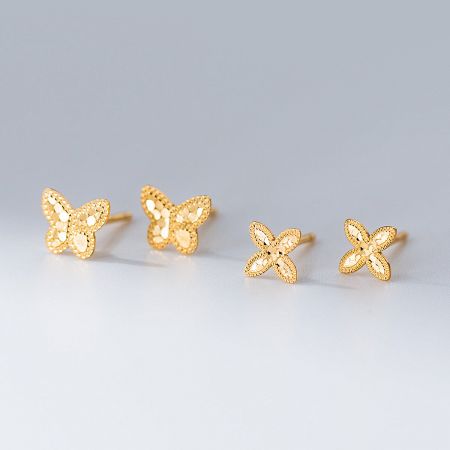 Close-up of the gold-plated 925 sterling silver butterfly and flower laser-cut stud earrings from the collection.