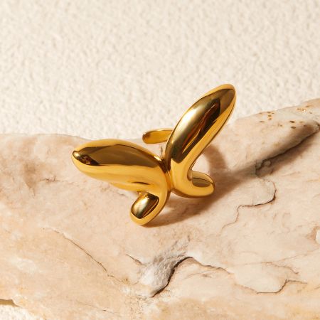 Close-up of the gold butterfly ring on a white marble surface.