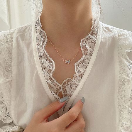 Another view of the butterfly necklace on a model with a white lace blouse.