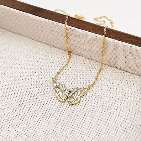 Close-up detail of the gold butterfly pendant with clear stones on a soft surface.