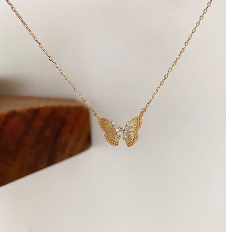 Detailed view of the butterfly pendant, highlighting the textured wings and sparkling cubic zirconia stones.